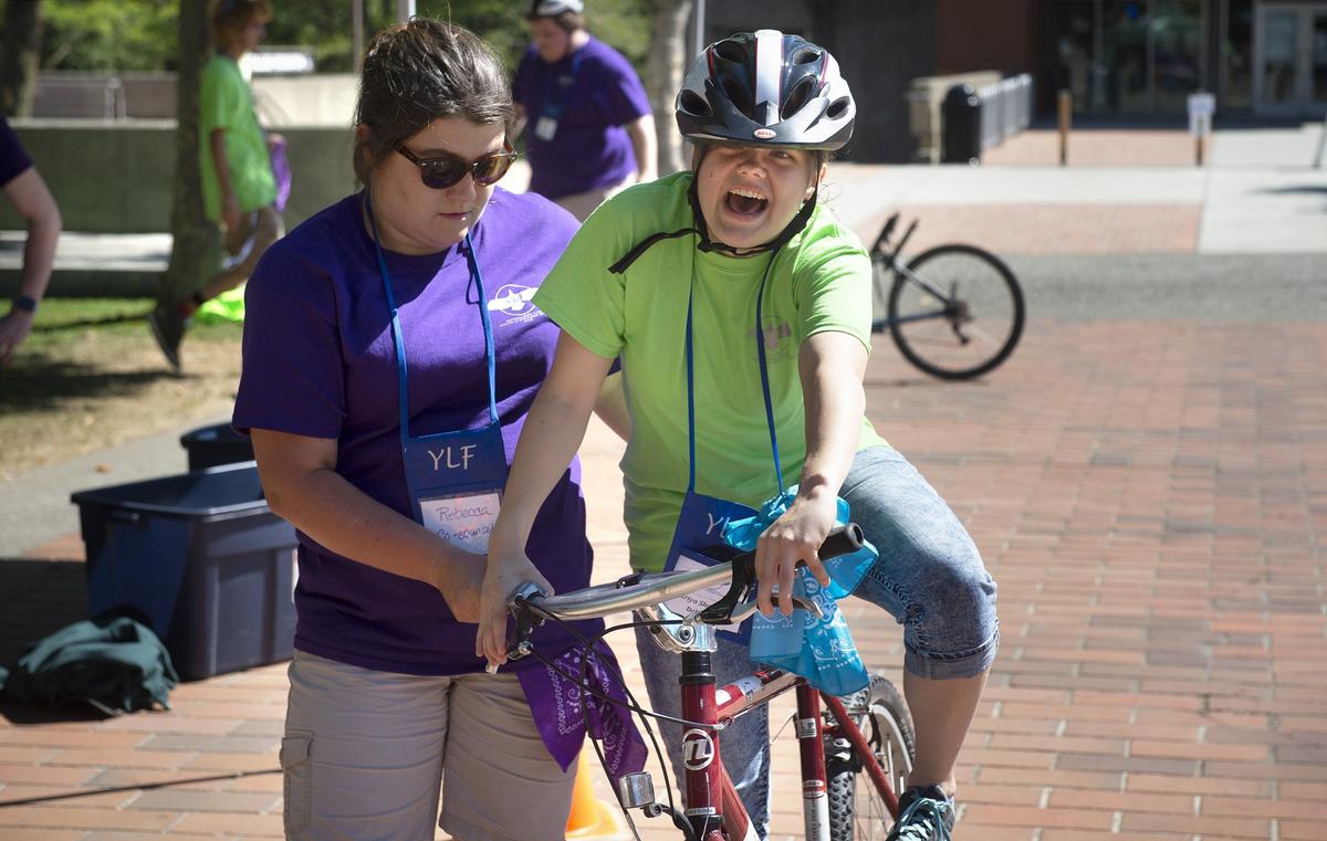 Counselor Rebecca Muchmore of Orting helps Mariya Shanygina as she rides a bicycle during the Youth Leadership Forum at The Evergreen State College in Olympia on Wednesday, July 25, 2018.