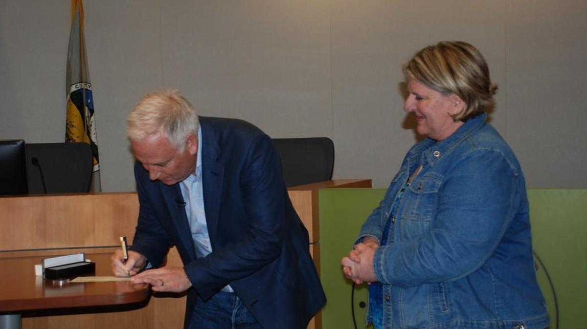 Karen Black, mother of fallen soldier Bryan Black, watches on as First Move: America’s Foundation for Chess founder Erik Anderson signs a $7,500 check to go toward a chess memorial for Bryan.