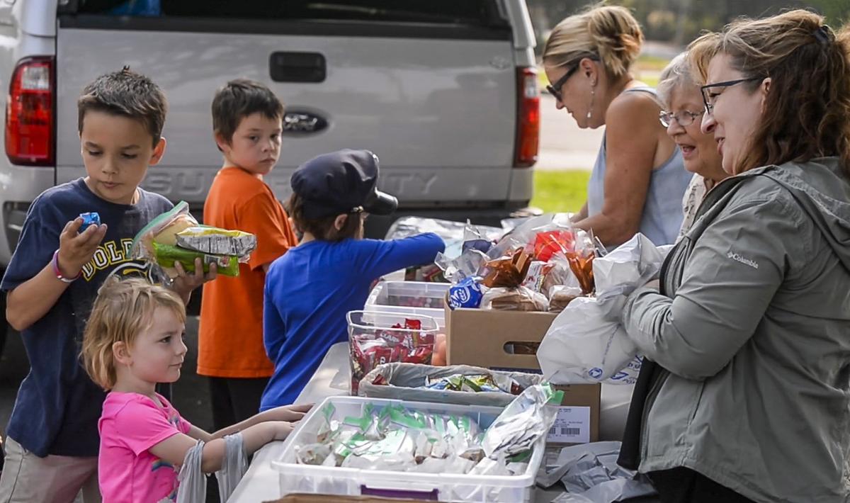 Kids grab the goods as Mother 2 Many volunteers give them attention and food in the Sumner Skate Park, Aug. 13.