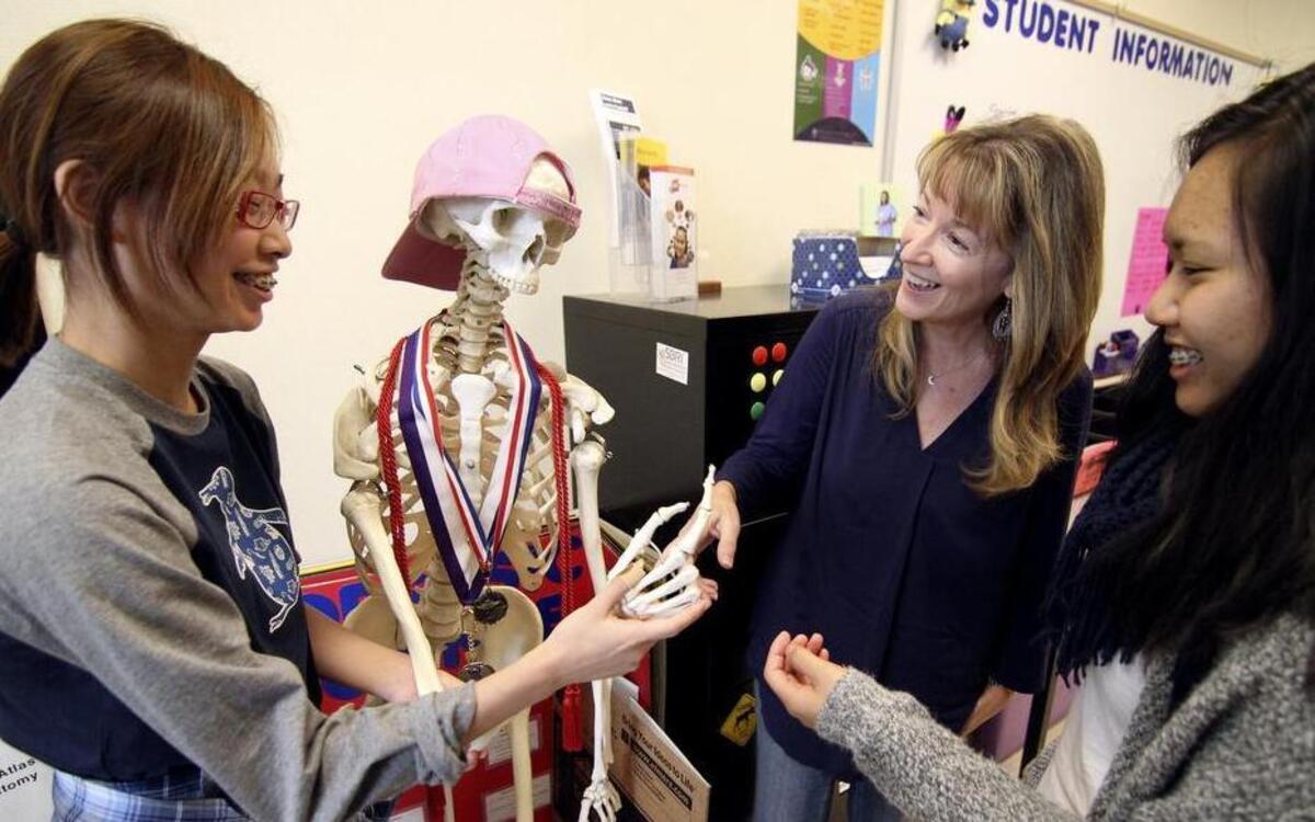 
Puyallup High School students Sara Son, left, and Elizabeth Luong look over a human skeleton last Friday with teacher Pam Reichel in her Anatomy and Physiology class.
