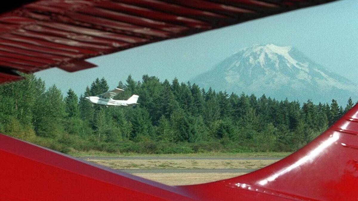A plane takes off from Thun Field with Mount Rainier in the background.