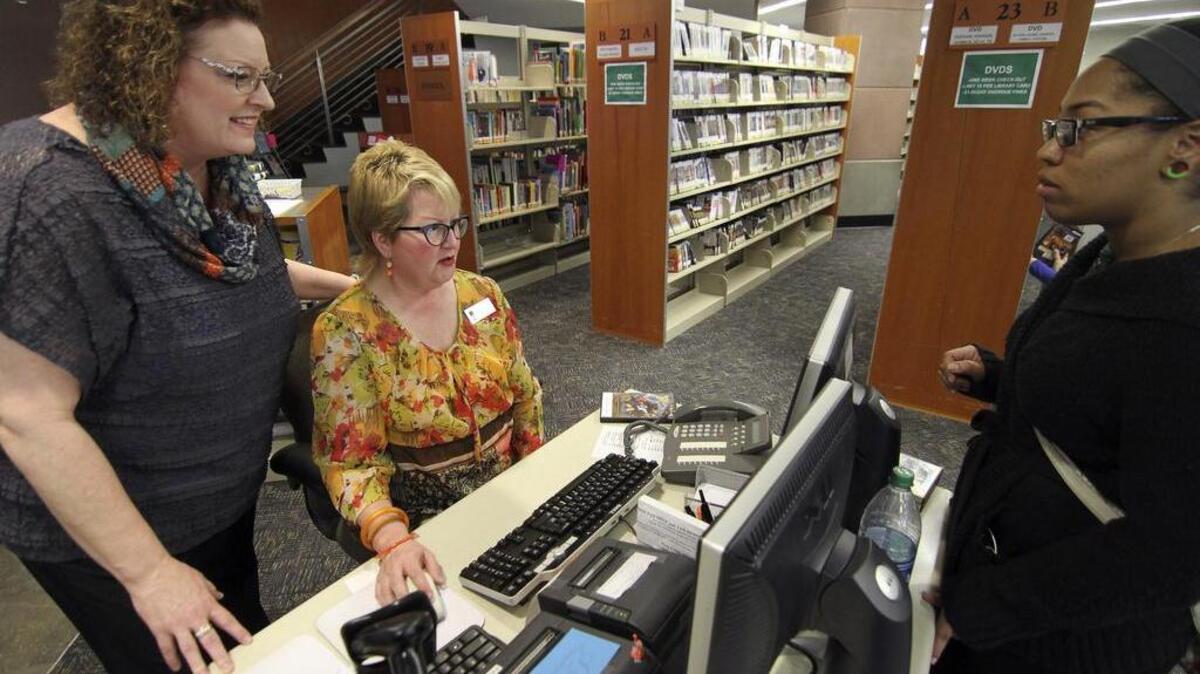 Puyallup Library director Patty Ayala Ross, left, and library assistant Debi Rinehart, center, help patron Staci Haynes. At an Aug. 22 meeting, the Puyallup Public Library Board passed an Unattended Child Policy, which was updated by Ross.