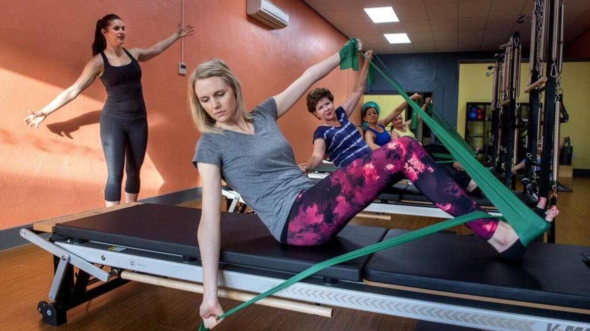 Owner Becky Reynolds, left, leads Stephanie Knapp and other clients through an exercise in her Inspired Movement Pilates studio in Puyallup on Friday.