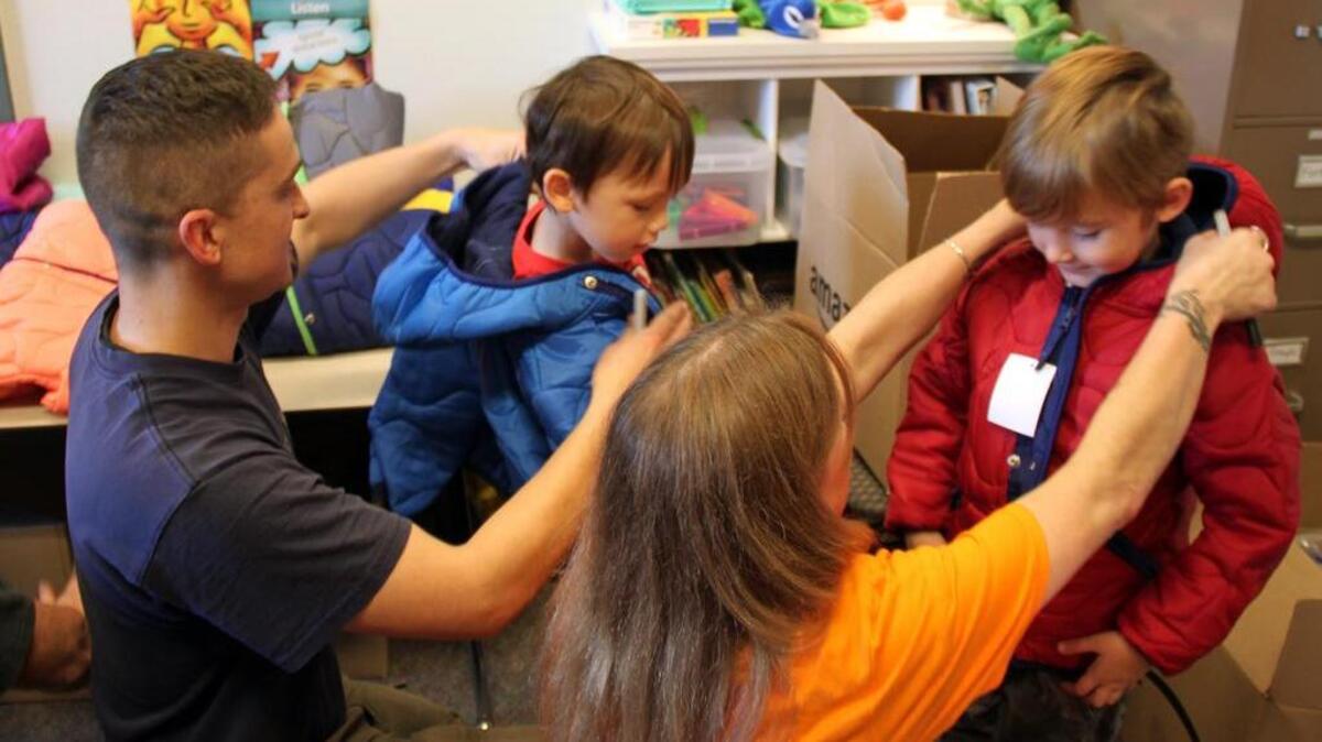 East Pierce Fire & Rescue firefighter-paramedic Mason Lewis and an Amazon associate help students at Daffodil Valley Elementary School in Sumner try on their new coats.