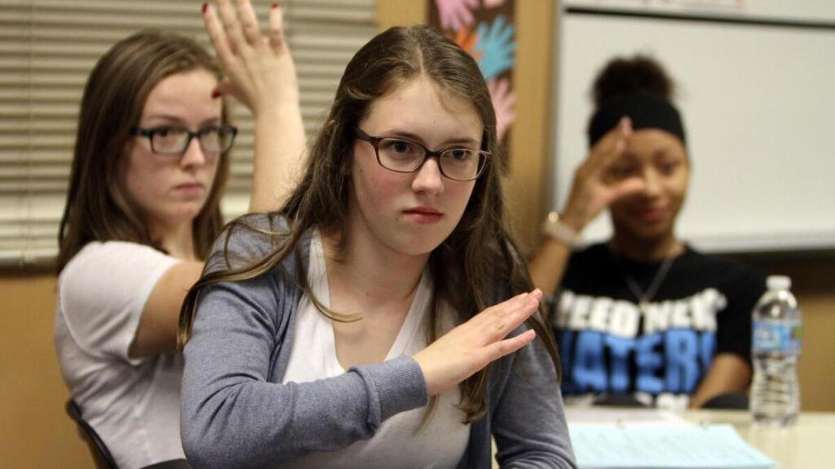 Emerald Ridge High School American Sign Language students Makenzie Meyer, center, Laura Gerolium, left, and Nioh Magroff follow along with teacher Mitch Noll last week during their classroom instruction.