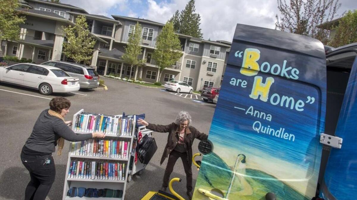 Gabby Fuentes, left, and Trina Germond, librarians with the outreach program of Pierce County Library, unload carts of books last week at Cedar Ridge, a retirement home in Bonney Lake.