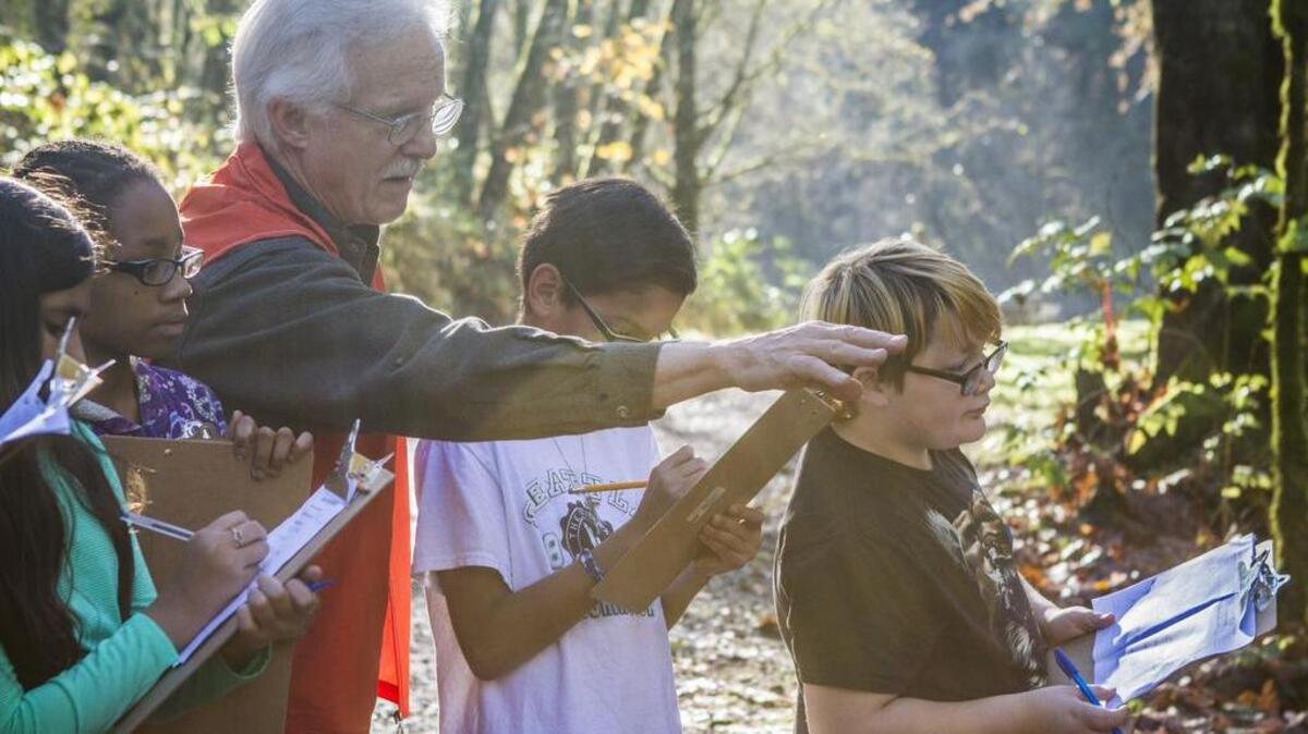Terry Maves, center, points out salmon to students as they talk about salmon migration at the Puyallup Fish Hatchery in Puyallup on Nov. 8.