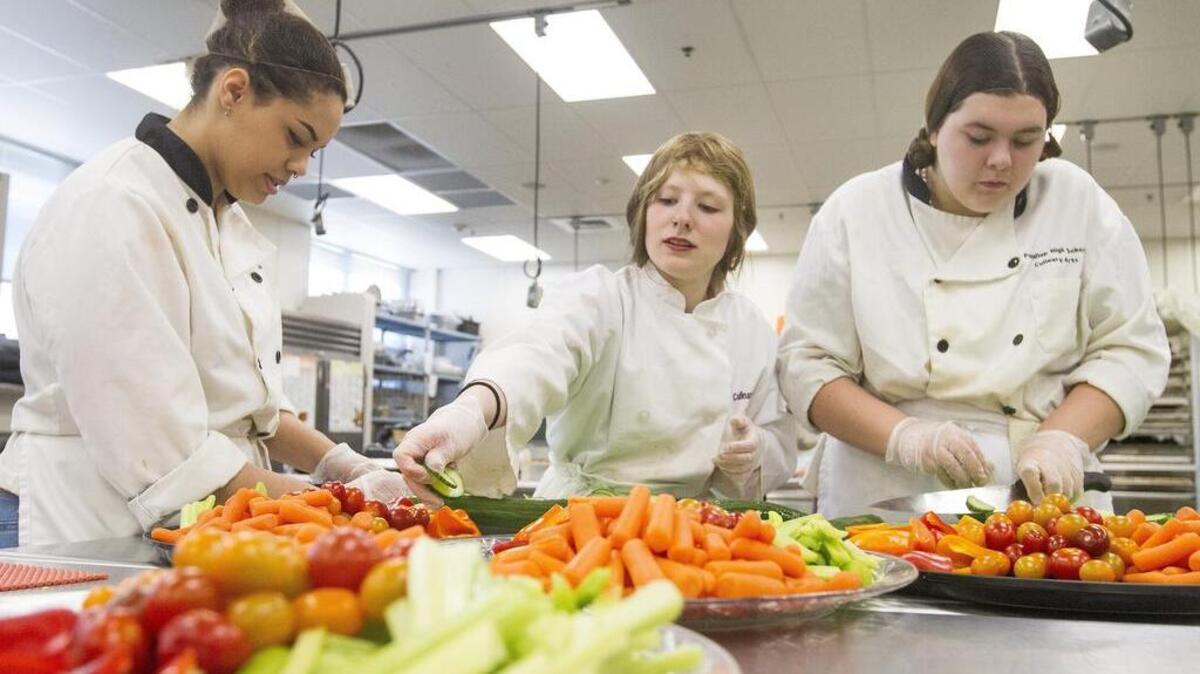 Puyallup High School students Lanae Haskell, Sydnee Murphy and Shania Seyler, from left, prepare vegetable trays during a culinary class last week at the high school.
