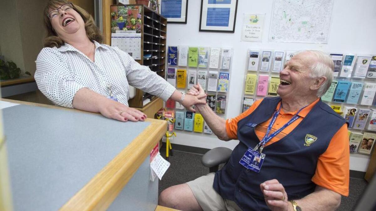 Lisa Isaacs jokes with volunteer Jim Maniatis as he mans the front desk at the Puyallup Police Department on Tuesday, May 23. Maniatis is a part of the Volunteers In Police Service (VIPS) program, one of many community involvement programs that Isaacs founded, including Coffee With A Cop and Paws On Patrol. After two stints coordinating crime prevention for the city (1999-2006 and 2012-present), Isaacs is retiring to enjoy her new grandaughter, time with her husband, retired Army Col. Tony Isaacs, and building community around their home on Fox Island. “I’m going to miss this community,” she said. “People here are super willing to help and want the best for their community.”