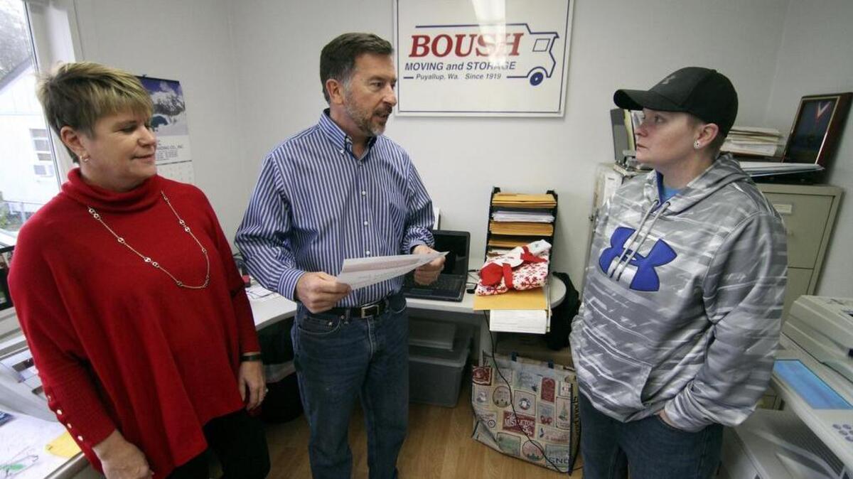 Boush Moving and Storage owner Carl Boush, center, presents a holiday season gift certificate to Puyallup resident Nicole Carroll, right, as Boush office manager Sue Hansen looks on last week at the Puyallup-based business. Carroll, who works as a pizza delivery driver while also attending Tacoma Community College studying accounting, got the gesture of goodwill to help her and her family to get back on their feet.