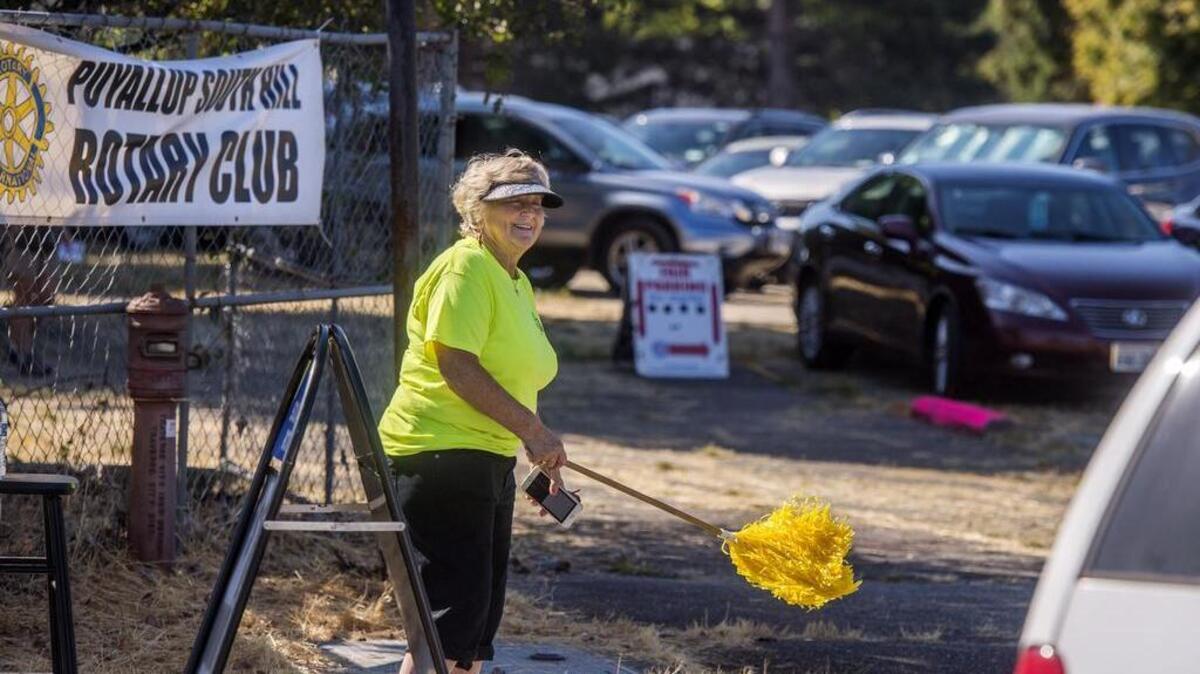 Kitty McGuane of South Hill waves cars into the “closest parking lot to the fair,” across Meridian Ave. from the Gold Gate of the Washington State Fair in Puyallup on Sept. 1. It has been operated by the South Hill Rotary for years, but this is expected to be the last one.