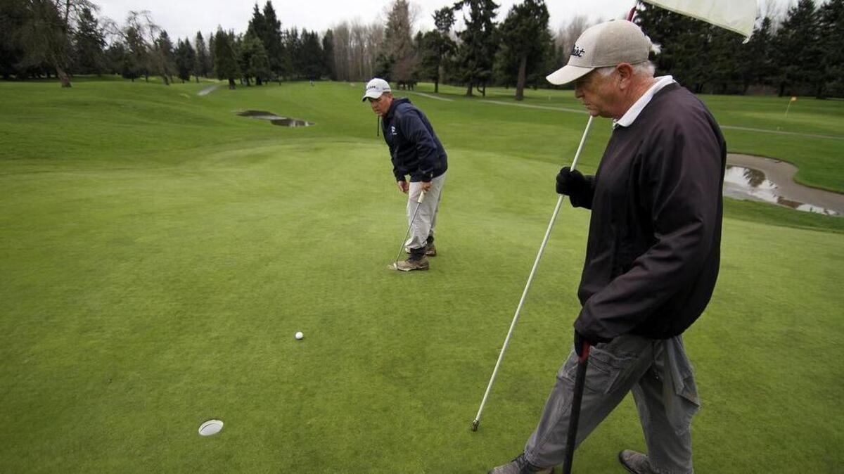 Chet Issac tracks his putt as fellow Linden Golf and Country Club member Guy Kuestermeyer looks on.