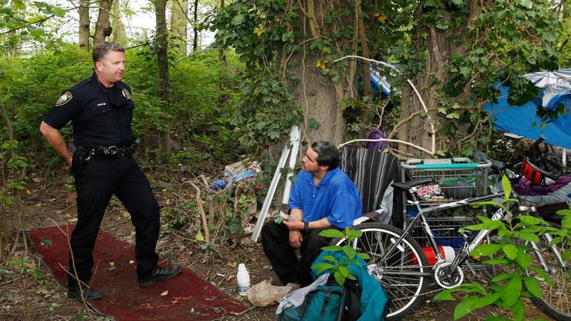 Community outreach officer Jeff Bennett of the Puyallup Police Department speaks with a homeless man named Enrique during a routine inspection of his camp last week.