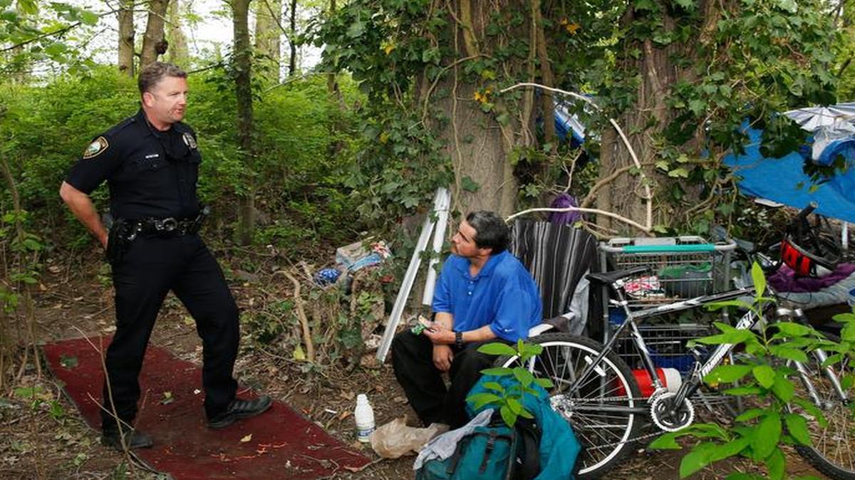 Community outreach officer Jeff Bennett of the Puyallup Police Department speaks with a homeless man named Enrique during a routine inspection of his camp last week.