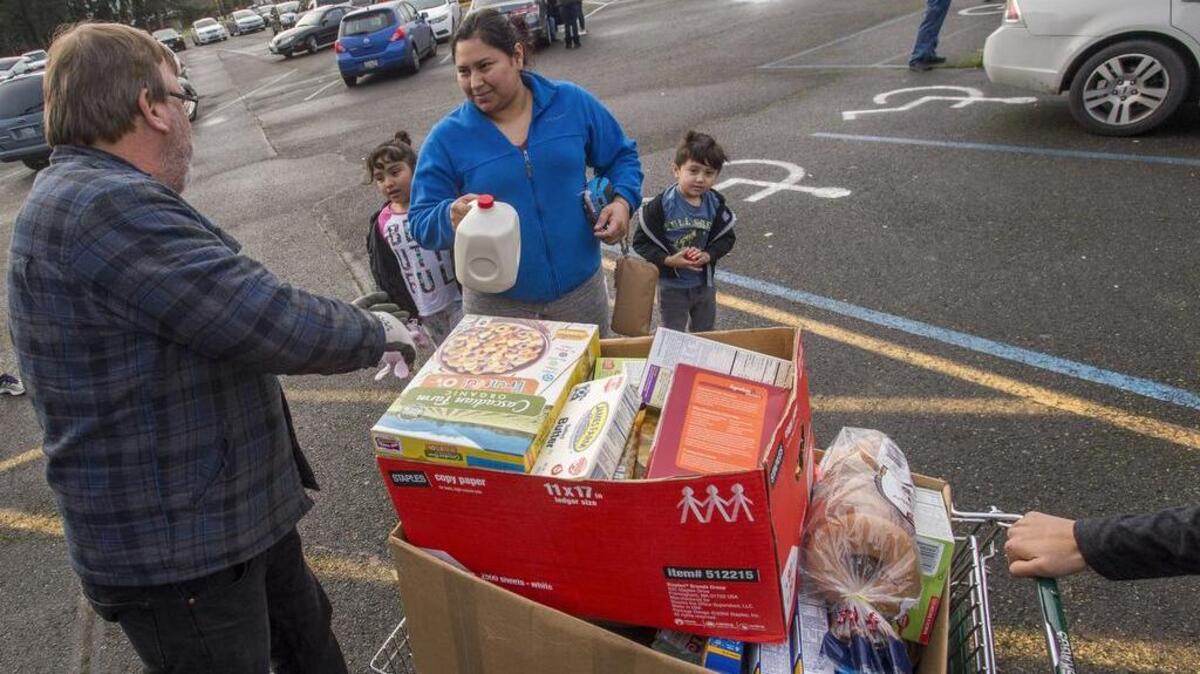 In the parking lot of the Puyallup Elks Club, Raquel Ibarra and her kids are given a shopping cart full of food for holiday dinners on Saturday, Dec. 16.