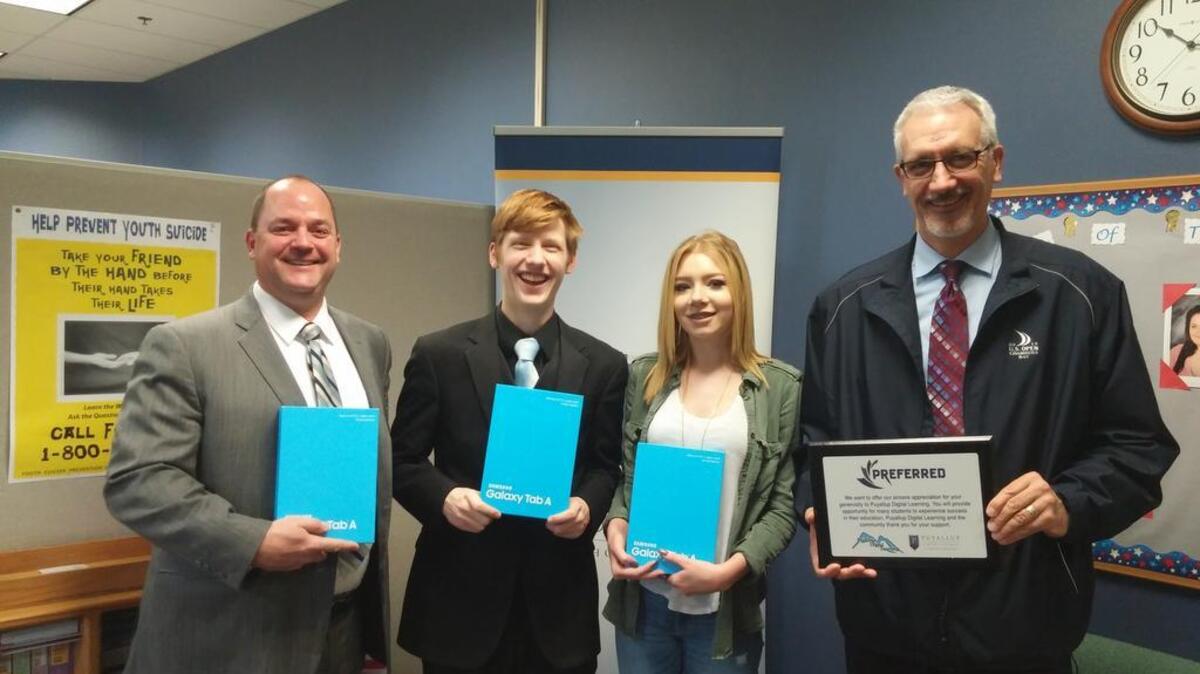 John Hale, vice president of sales for Preferred Business Solutions, and branch sales manager Scott Armstrong, far right, present 10 donated tablets to the Puyallup School District’s Digital Learning program. Students Christopher Wallitner and Shelby Woodard proudly hold the devices.