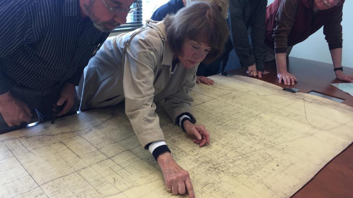 Wayne Fass, Randa Conroy, Linda Lang, Chris Chisholm and Andy Anderson, from left, look over an old map of Puyallup. As members of the Puyallup Historical Society, they are collaborating with the city of Puyallup to host the Community Historic Preservation Day on Saturday (May 20).