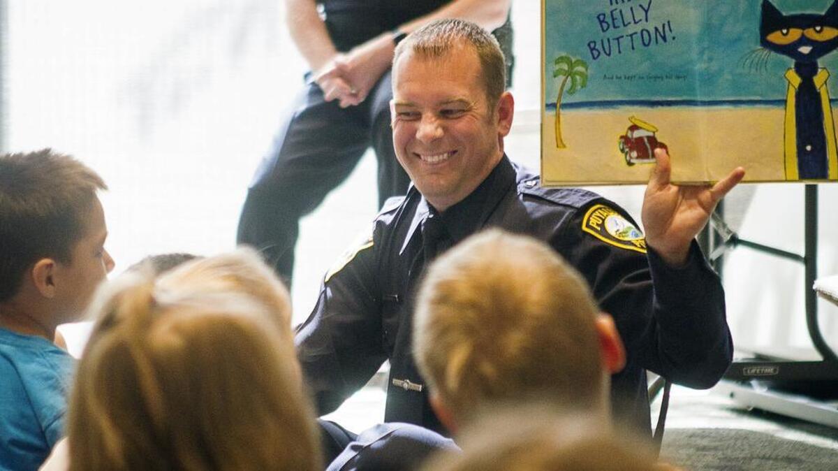 Officer Mark Ketter smiles as he reads books to kids during the Superheroes at Storytime event at the Puyallup Public Library on Friday.