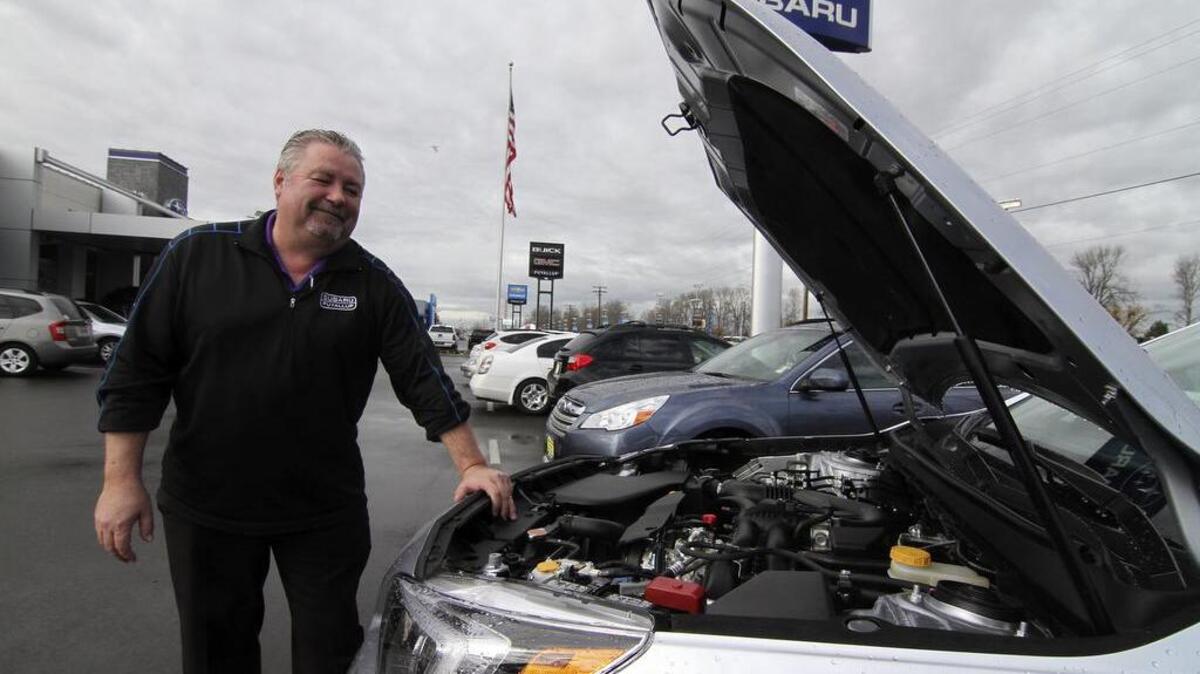 Subaru of Puyallup salesman Dave Warmack looks over a new car on the lot along River Road in Puyallup. The Subaru dealer, part of the Harnish Automotive Group, is expanding its retail space by building a multi-floored parking structure.