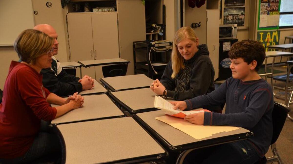 Ballou Junior High teachers Troy Halfaday and Tamara Chipps watch as Jared Fischer shows his best work to his mother, Amanda, during a student-led conference last week at the school. Amanda, a staff sergeant in the U.S. Air Force, recently surprised Jared on her return from a months-long assignment overseas.