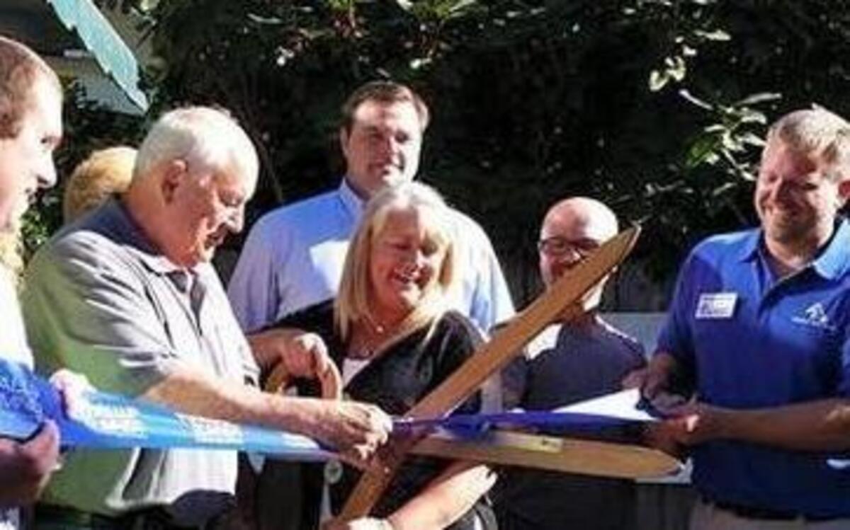 
Duke Paulson, far right, and Trish Cole, left, along with other community dignitaries, gather to cut the blue ribbon on the second duplex donated to Helping Hand House from South Hill Rotary during a ceremony July 28.
