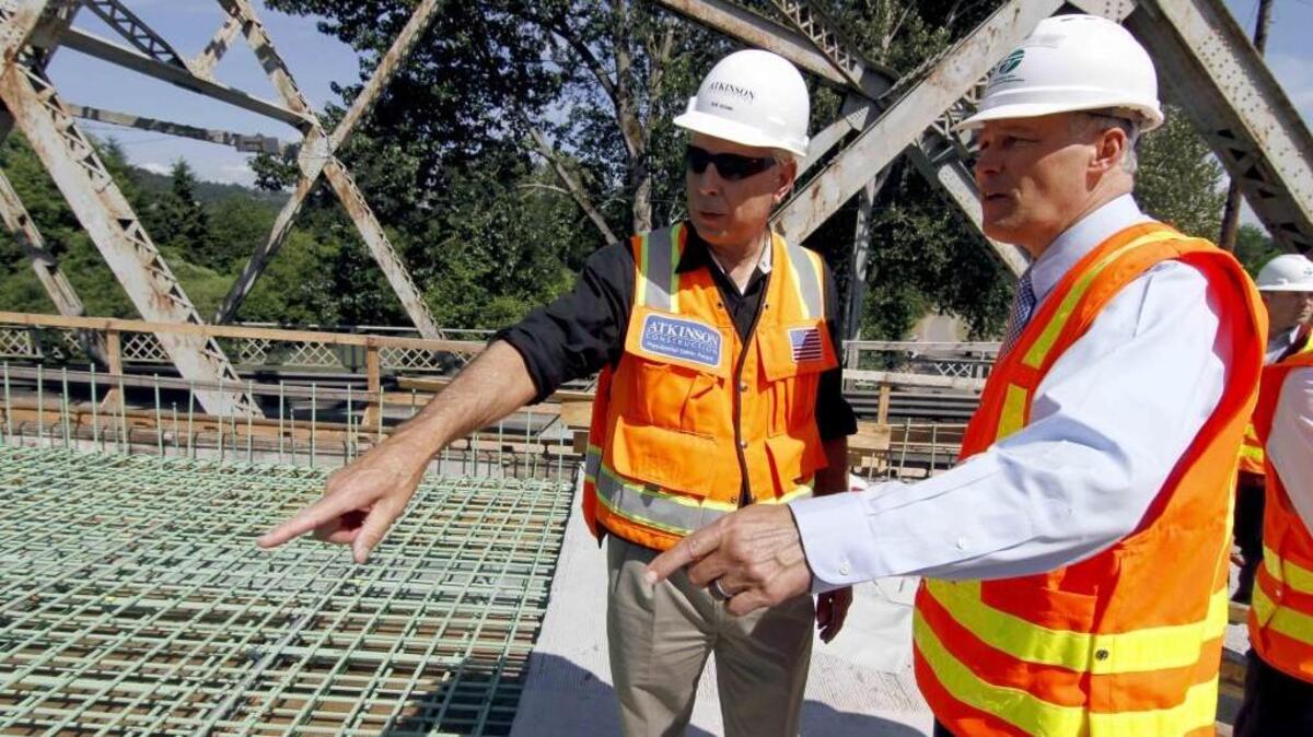 Atkinson Construction Senior Vice President Bob Adams, left, talks about the new Meridian bridge construction project over the Puyallup River with Washington Gov. Jay Inslee during a tour of the project in May.