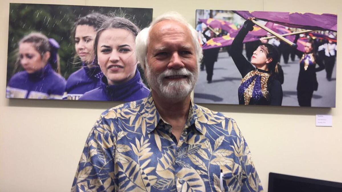 James Martinson stands before two of his street photography pieces from last year’s Daffodil Festival in Puyallup. The photos are on display in the city art gallery at City Hall through December.