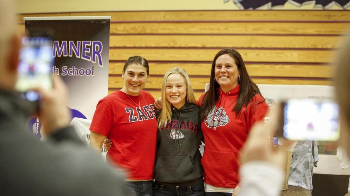 Jordan Thompson poses for photographs with coaches Cami Schultz, left, and Robi Turley, right, during a celebration for Thompson at Sumner High School on Jan. 11.