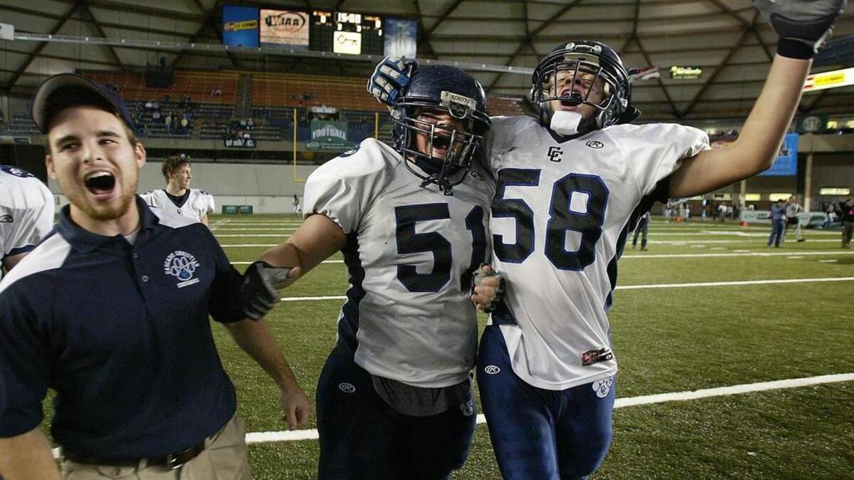 Devin Snyder, left, seen here celebrating with Cascade Christian High players after winning the 2014 Class 1A state championship, has been hired by Lakes High to become the Lancers’ new defensive coordinator.