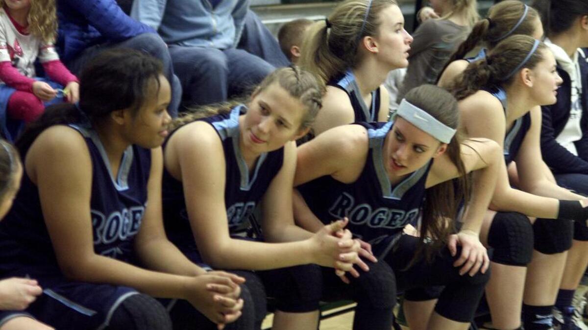 Being able to sit on the Rogers High girls basketball bench is special for KC Catey, center, as she overcame the temporary loss of the use of her legs after a golf swing nearly took her athletic career away from her.