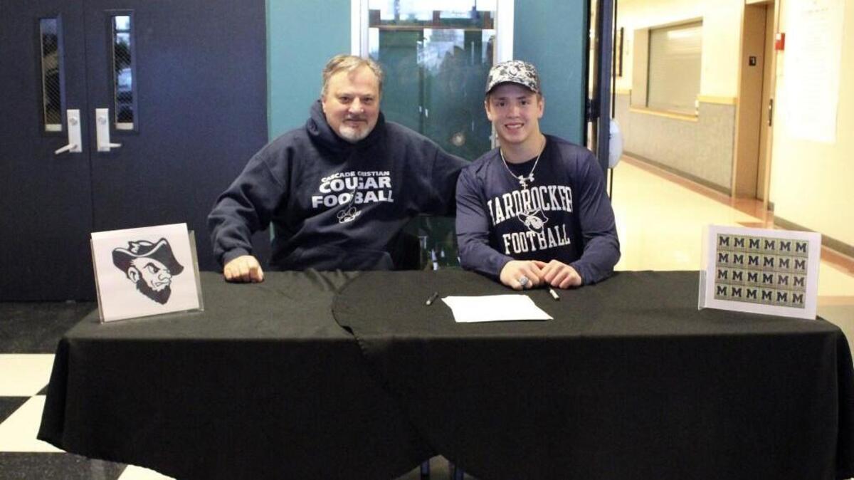 Josh Seaton, right, takes pictures with Cascade Christian coach Randy Davis after the senior signed on to play safety for South Dakota School of Mines and Technology on Feb. 3.