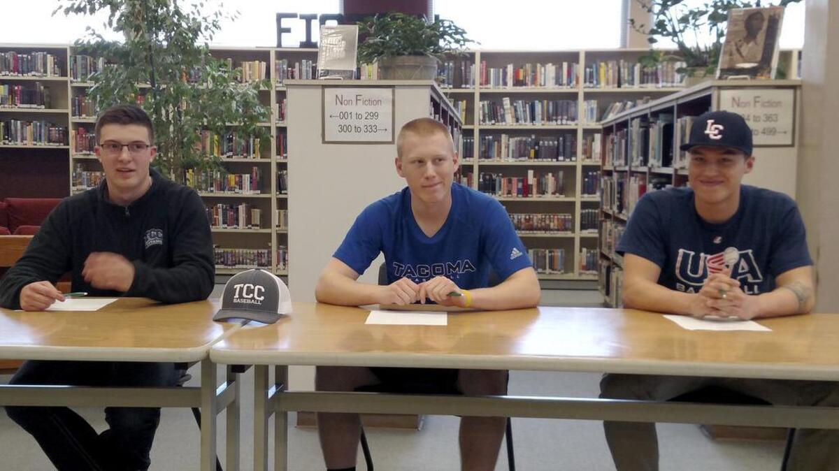 Puyallup High baseball players Kenton Robillard, left, and Collin Wolf, center, sign letters of intent Friday morning to play baseball with Tacoma Community College, while Ryan Peterson, right, signs his commitment with Lewis-Clark State in Idaho.