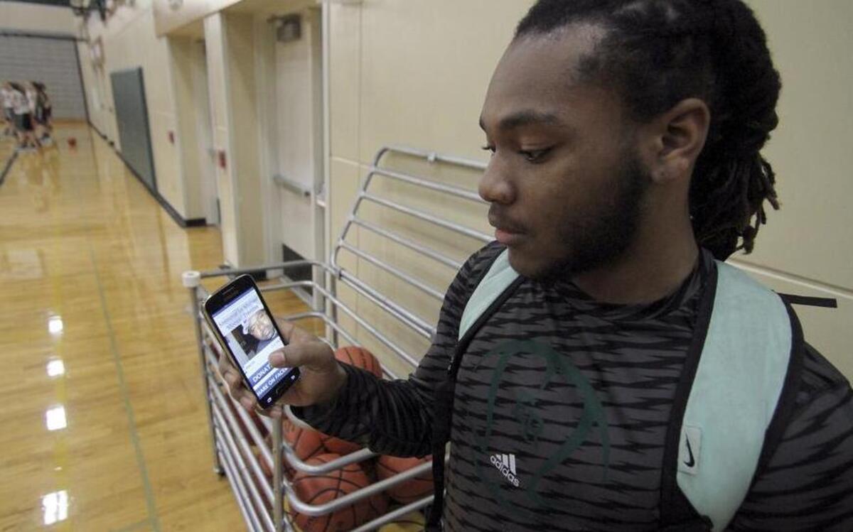 Emerald Ridge High senior Raeshon Scales looks at a photo on his phone of his father, Michael Tremble, who passed away during last season.