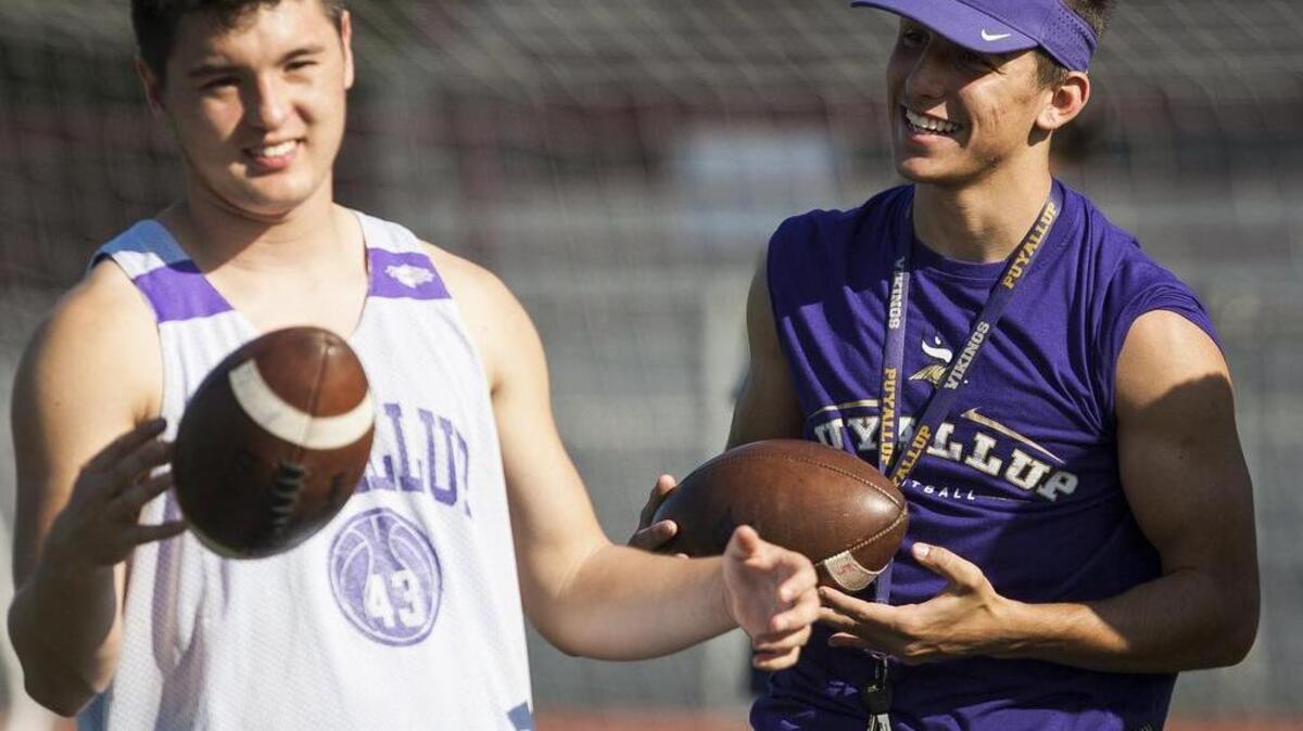 Puyallup High quarterback Nathaniel Holcomb and wide receiver Noah McFadden talk during camp last week at Sparks Stadium in Puyallup.