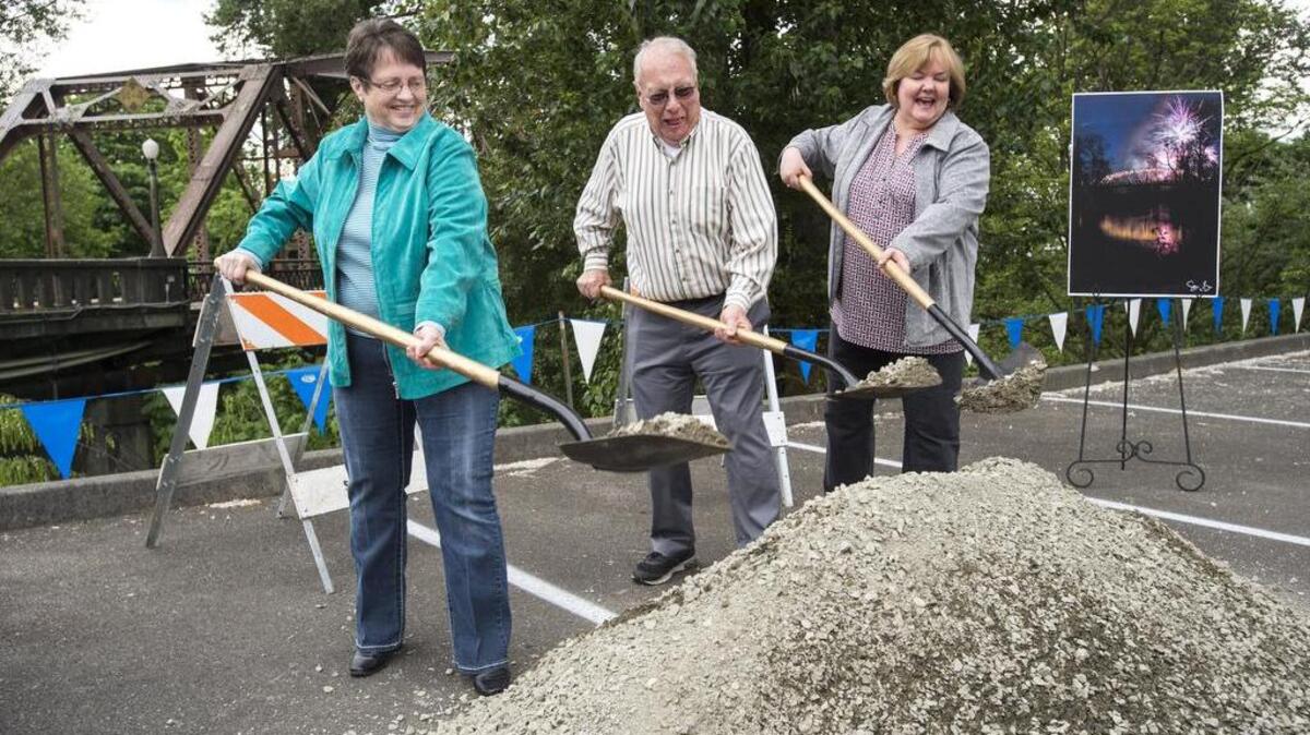 Sumner dignitaries scoop up ceremonial dirt and gravel at the groundbreaking for construction of the new Bridge Street Bridge. The old bridge is in the background. From left: Deputy Mayor Kathy Hayden, Mayor Dave Enlsow and Sumner City Council member Cindi Hochstatter.