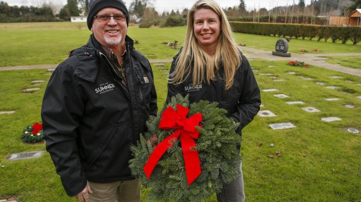 Cemetery administrative manager Scott DeCarteret and cemetery operator Kate Moore hold a wreath available for sale at the Sumner Cemetery in Sumner.