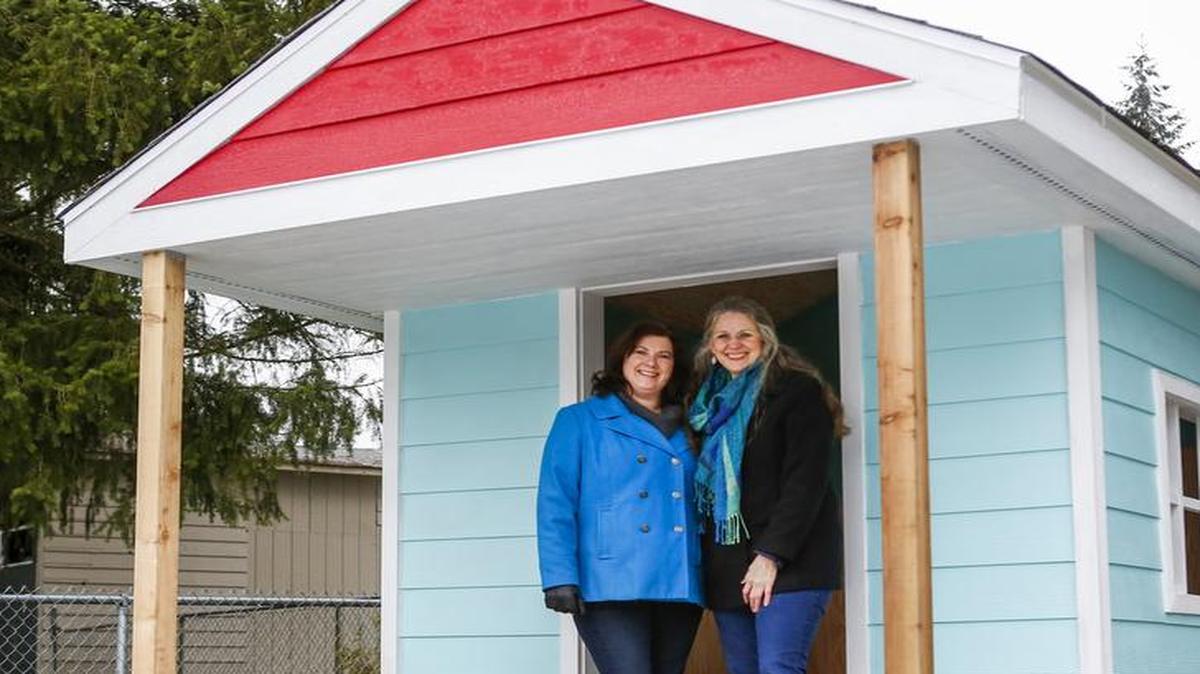 Kimberly Caldwell, Prairie Ridge Community Coalition leader, left, and Sue Z. Hart, founder and CEO of Building Beyond the Walls, stand inside the playhouse given to the Prairie Ridge Community Coalition to put in Grandpa Lou’s Play Yard.