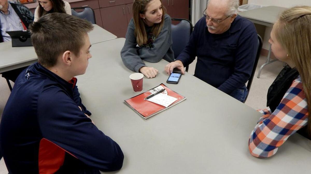 Sumner High School students Collin Stevens, left, Maggie Moffat, center, and Bailey Hazzard help Don Frazier figure out some of the finer details of his iPhone during a technology class last week at the Sumner Senior Center.