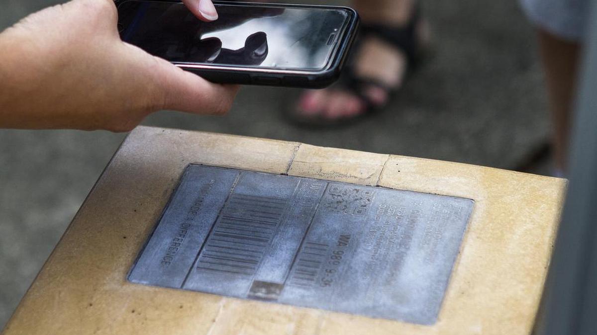 A person scans a QR code on a statue which pulls up a special webpage with more information.