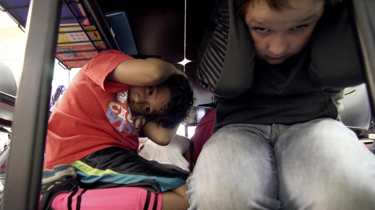 Maple Lawn Elementary School fourth-grader Diego Morales and deskmate Samuel Sharey, both 9, take cover under their desk during an earthquake drill Oct. 15 at the school.