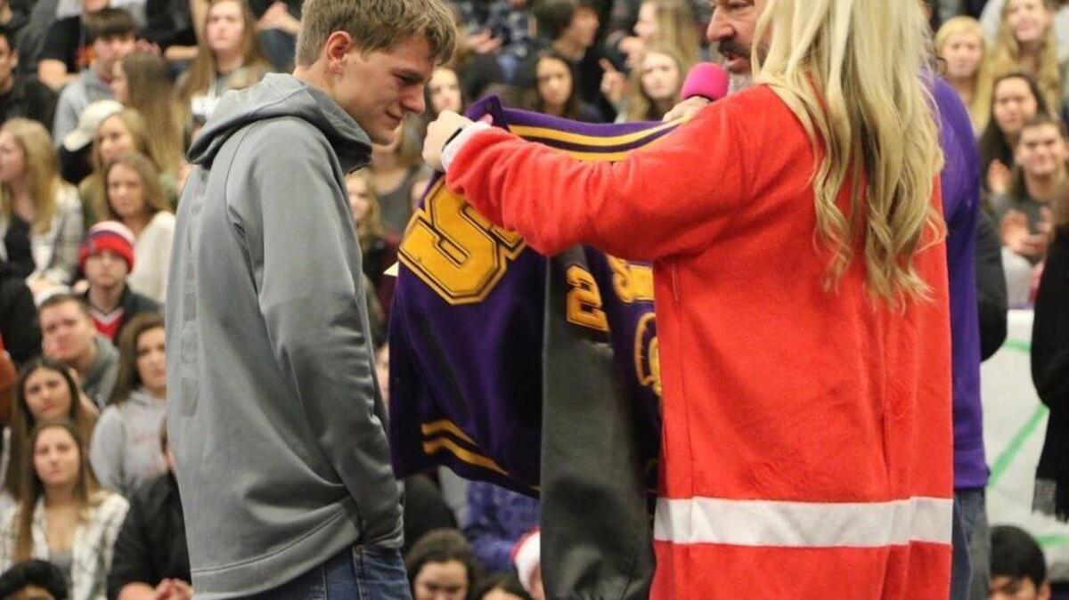 Senior football player Jason Holler receives a letterman jacket from coach Keith Ross and teacher Jordan Moog on Friday at the Winter Wishes assembly.