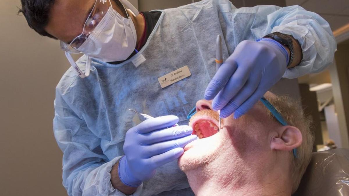 Dr. Andrew Kurialacherry on Saturday examines a possible abscessed tooth in the mouth of a patient taking advantage of Free Dental Day.