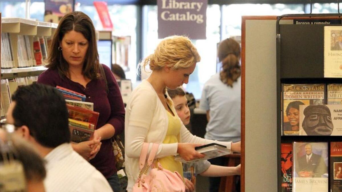 Dottie Metsker, Courtney Mathey and Kole Metsker, 7, standing from left, check out some of the offerings at Pierce County Library’s South Hill branch in 2010.