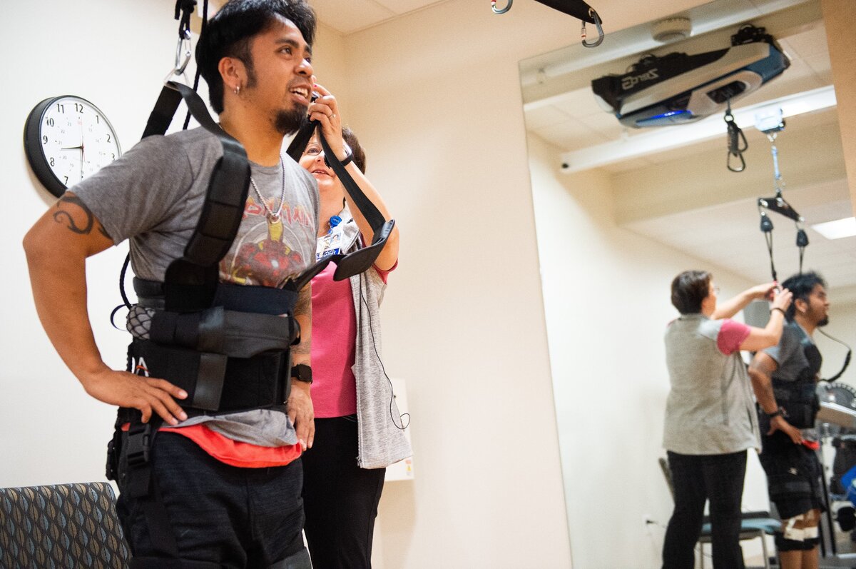 Physical therapist Noelle Buell helps Mike Sebastian, a patient at MultiCare Good Samaritan Hospital, pull of his harness for a quick break during physical therapy.  ZeroG Gait & Balance System is a computer-controlled harness that hangs from the ceiling to help steady patients as they undergo physical therapy.