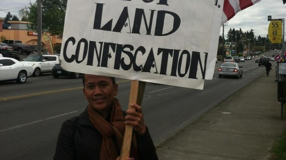 Sovong Voeuk of Renton holds a sign reading “Stop land confiscation” during a protest of the Cambodian government Monday in Tacoma’s South End. Protesters believed Prime Minister Hun Sen’s son, Lt. Gen. Hun Manet, would be at the hotel.