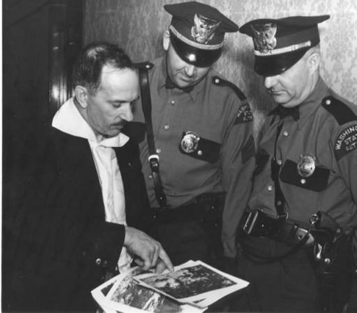 Washington State Patrol officers review crime-scene photographs from the kidnapping of Tacoma’s Charles Mattson, with an unidentified man. Mattson, 10, was kidnapped for ransom on Dec. 27, 1936. His battered body was recovered Jan. 10, 1937 in Everett. His murder was never solved. Frank Olson, a mental patient at Medical Lake Asylum, confessed to kidnapping the Mattson boy. Olson, also known as Lester Mead and Charles Thorp, was found harmless and was returned to the asylum after two days of questioning by the State Patrol at the Winthrop Hotel.