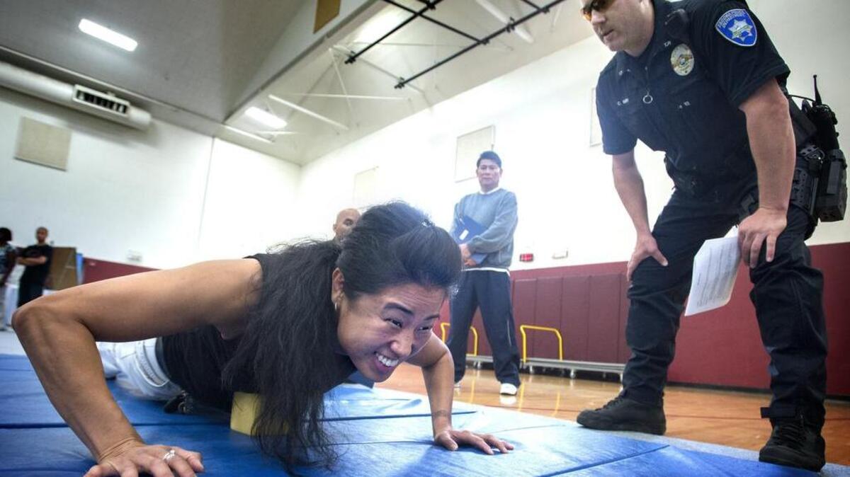 
Sarah Bucher of Tacoma grimaces while doing push-ups as Tacoma police officer Cory Smith monitors the exercise during the Diversity Job Fair at Bethlehem Baptist Church in Tacoma on Saturday. The department, which is about 87 percent white, is looking for more diverse recruits. 
