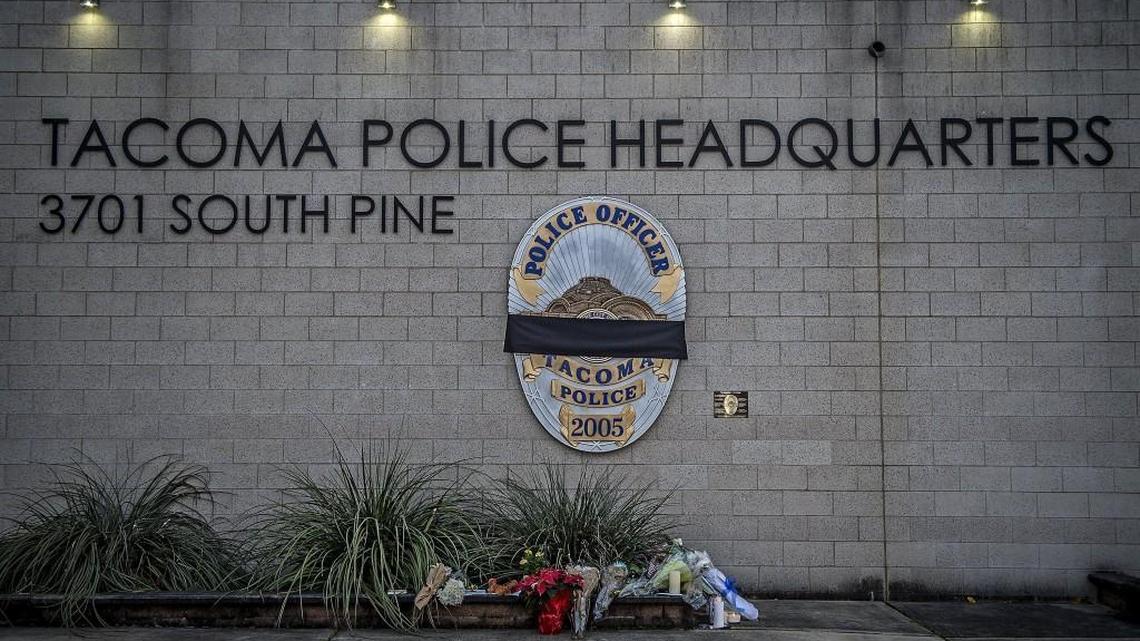 A black band has been placed over the shield in front of the Tacoma Police Department headquarters on Pine Street in Tacoma. A police officer was shot dead while responding to a domestic violence call shortly before 4 p.m. Wednesday.