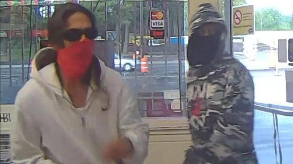 Two suspects are seen robbing a Lakewood grocery store Wednesday in this image from a surveillance camera.