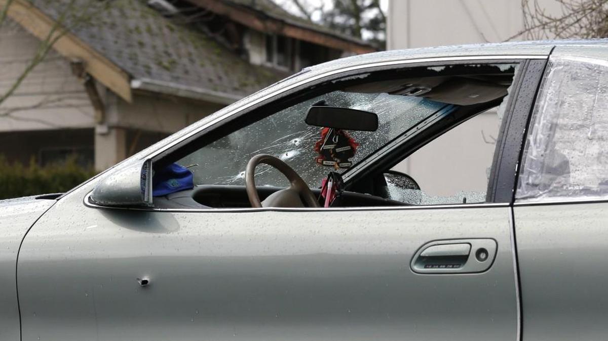 Bullet holes can be seen as a tow truck takes away a car Friday that was being driven by a woman who was fatally shot by police overnight after authorities said she accelerated toward them in Tacoma, Wash. Police were still searching Friday afternoon for a passenger in the car who fled with a rifle.